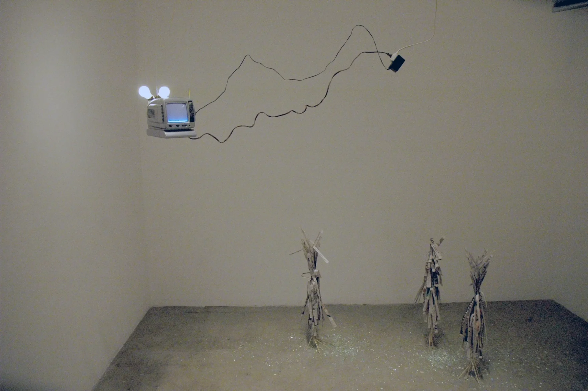 A room with three sculptures and a television on the wall.