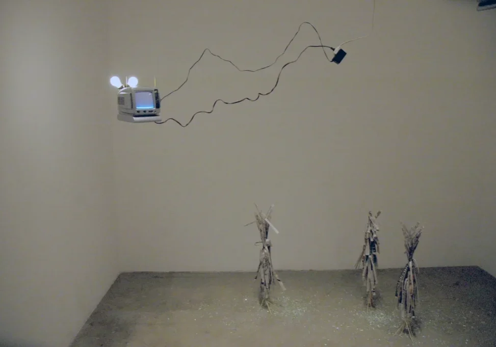 A room with three sculptures and a television on the wall.